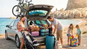 Familie vor gepacktem Auto im Urlaub. Der Kofferraum steht offen